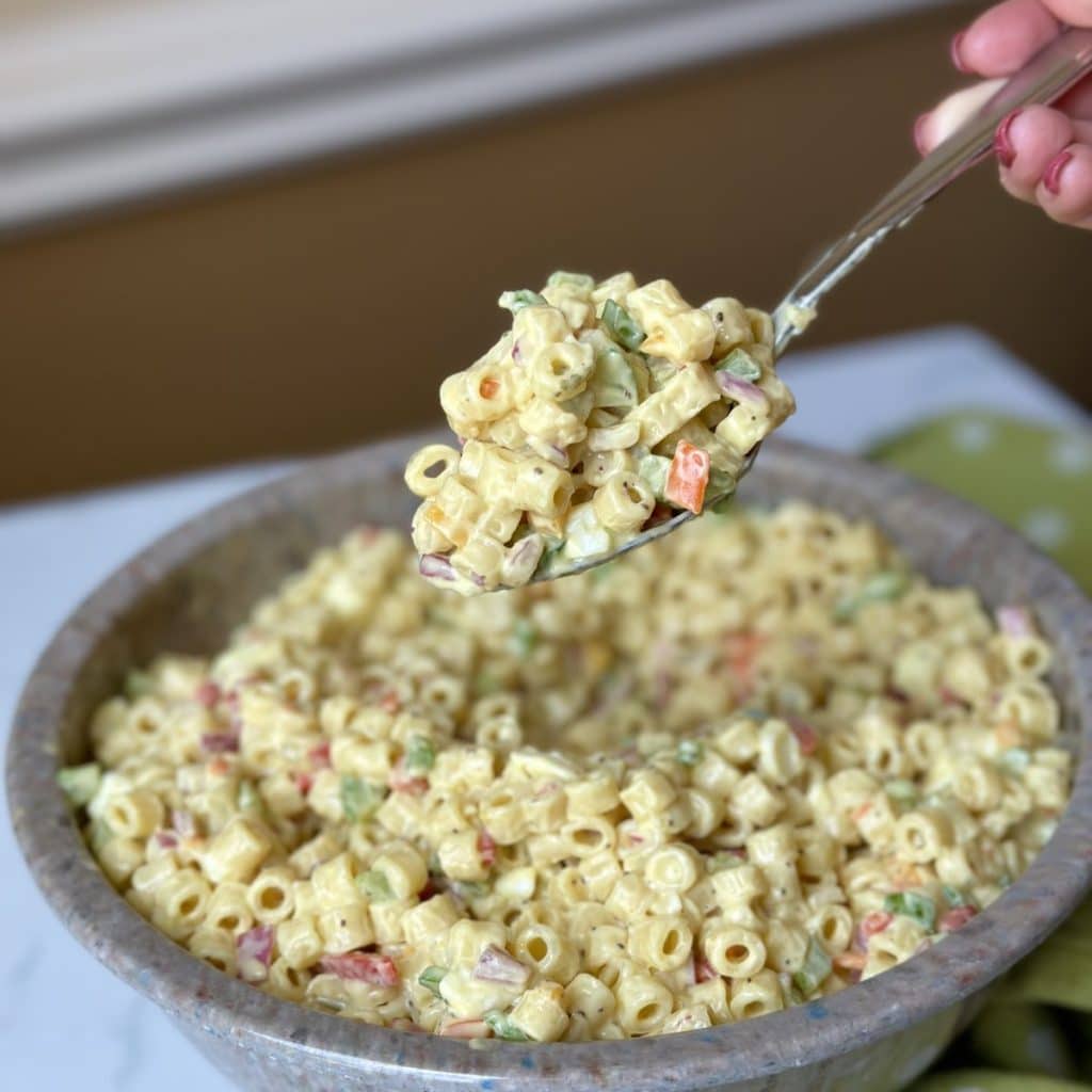 A bowl of pasta salad with a spoon.