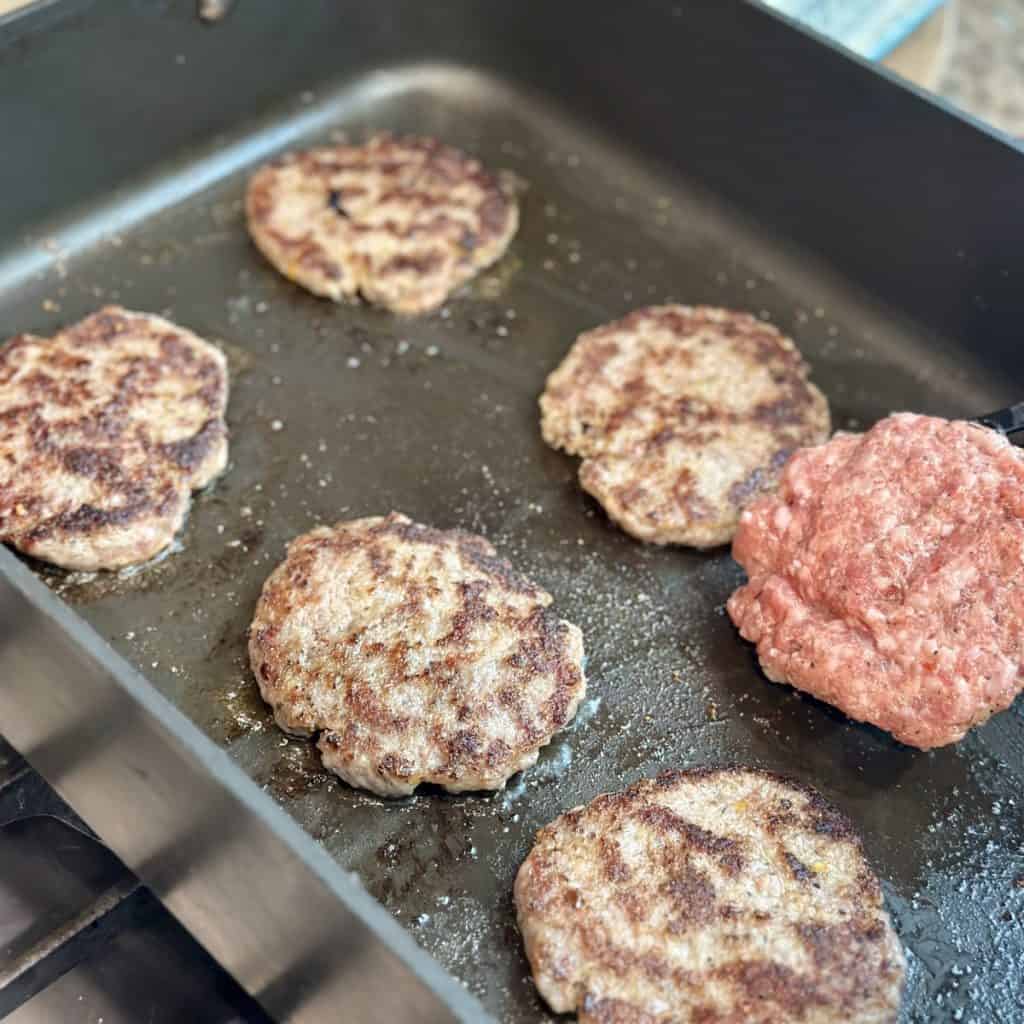 Searing sausage in a skillet.