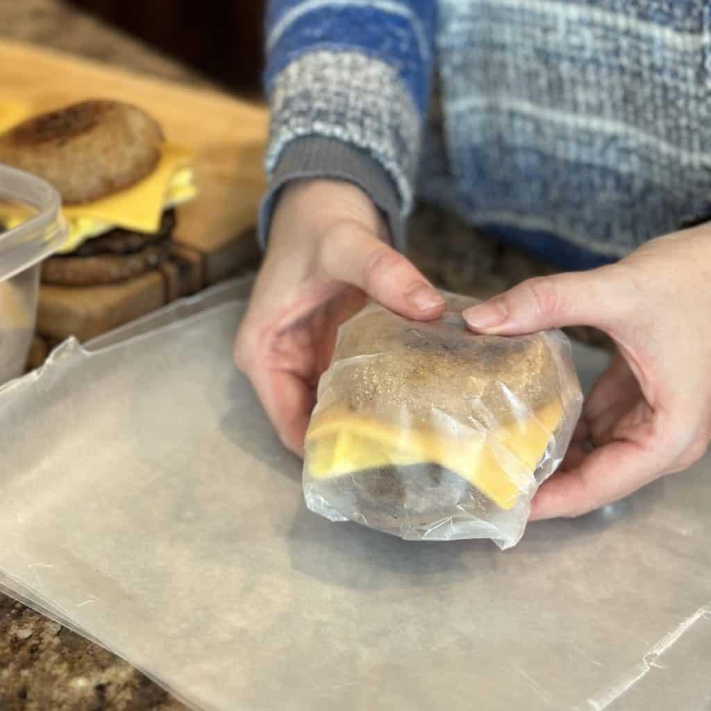 Holding a wrapped up breakfast sandwich ready to be reheated.