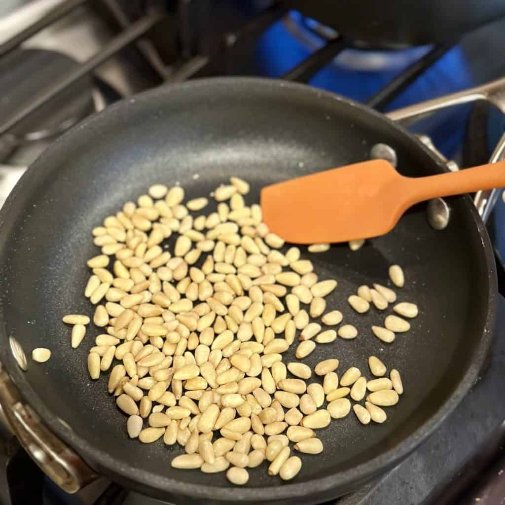 Toasting pine nuts in a skillet.