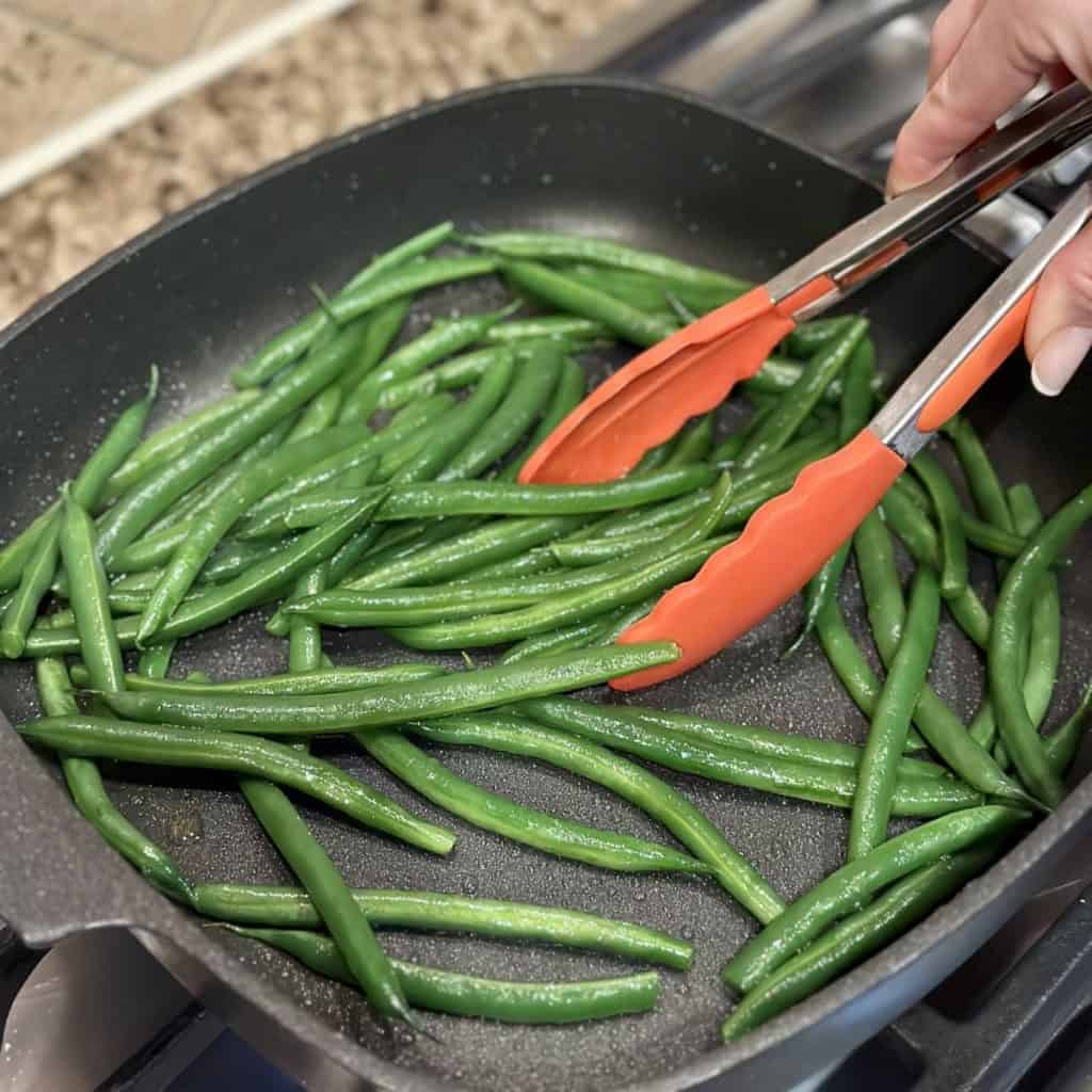 Sautéing green beans in a skillet.