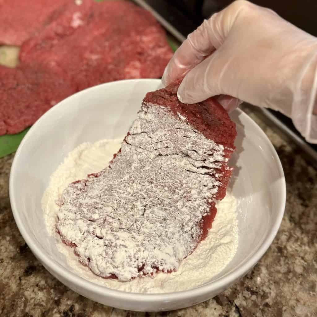 Coating cube steak in flour.