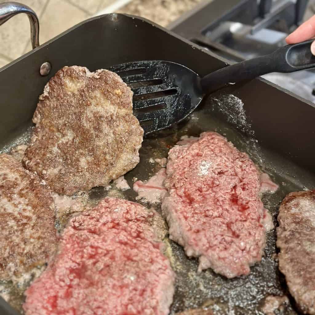 Flipping cube steak in a skillet.