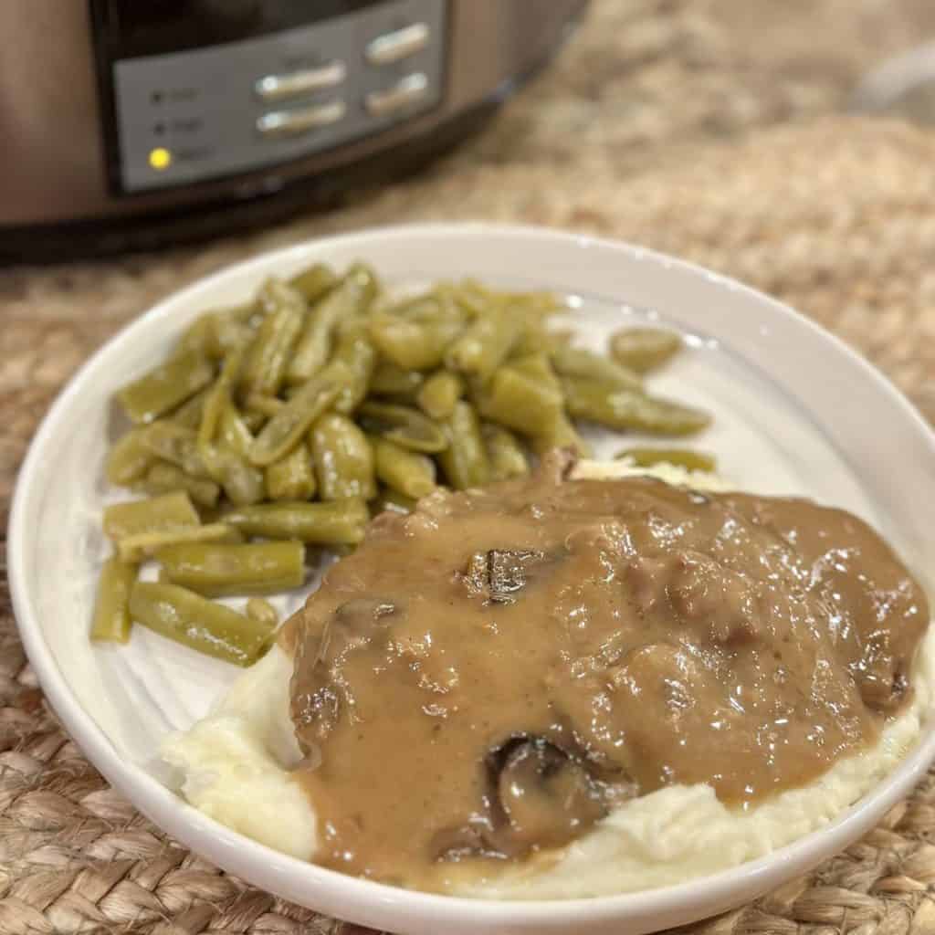 A plate with cube steak, potatoes and green beans.