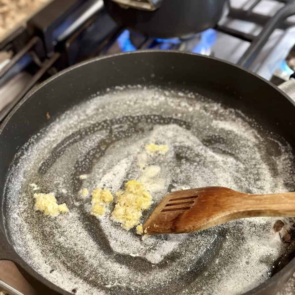 Sautéing garlic in butter in a skillet.