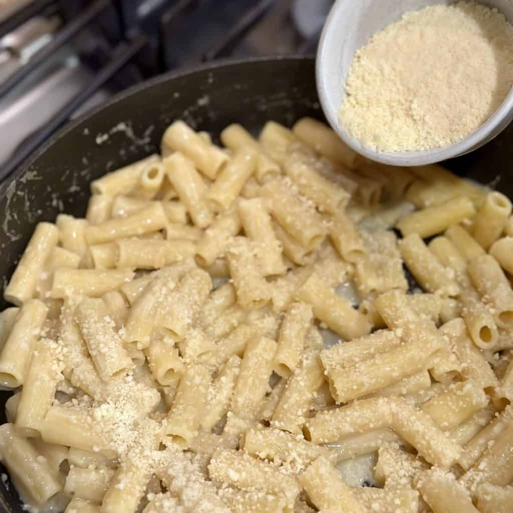 Adding parmesan cheese to pasta.