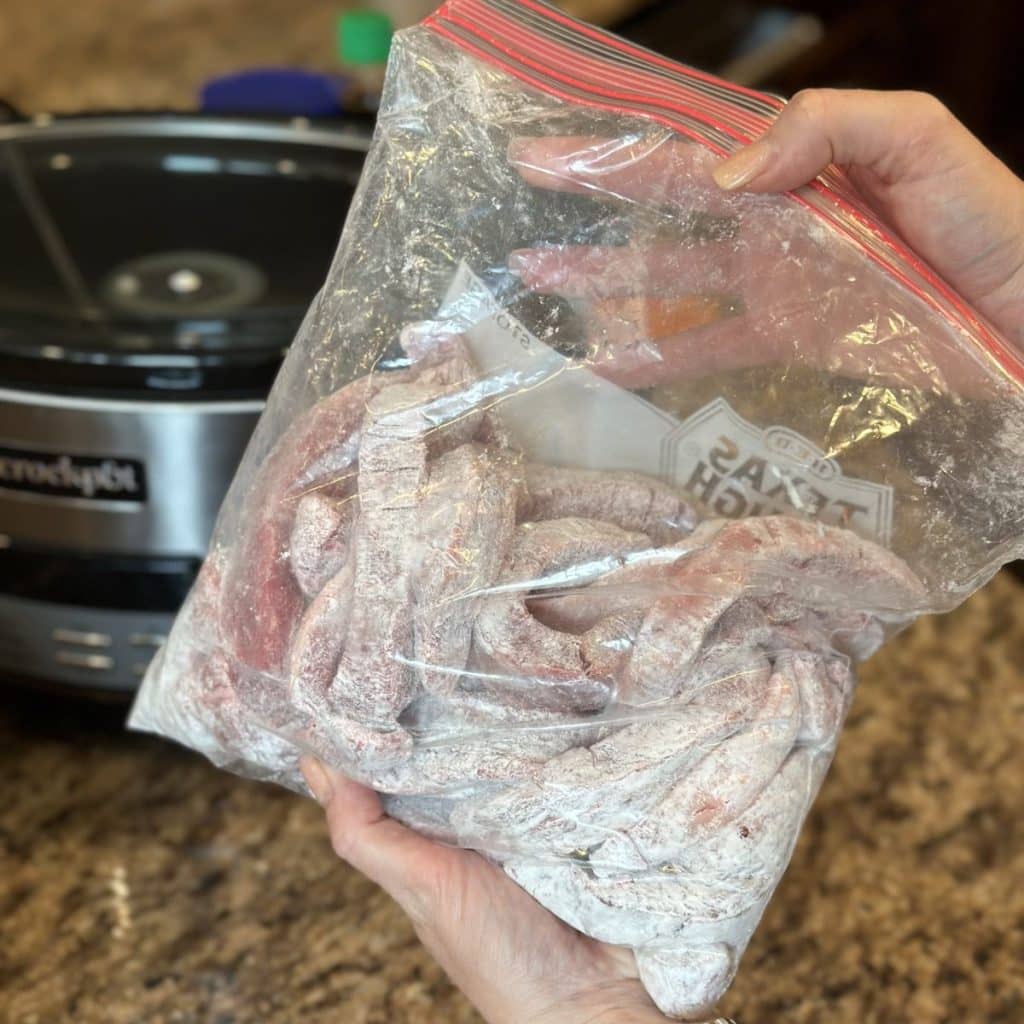 Shaking flank steak in cornstarch in a plastic bag.