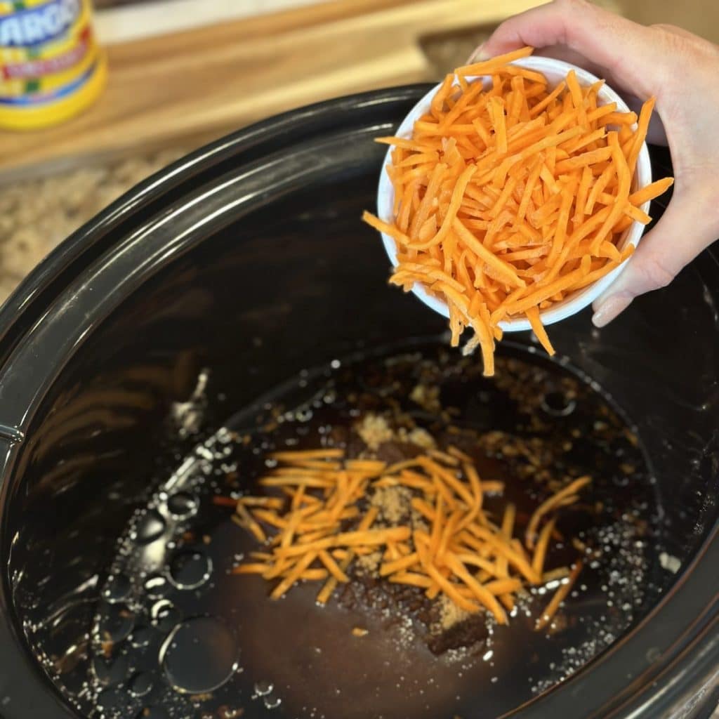 Adding carrots to a crockpot.