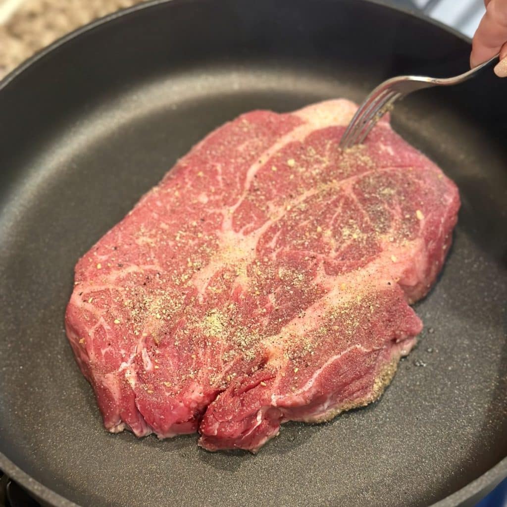 Searing a chuck roast in a skillet.