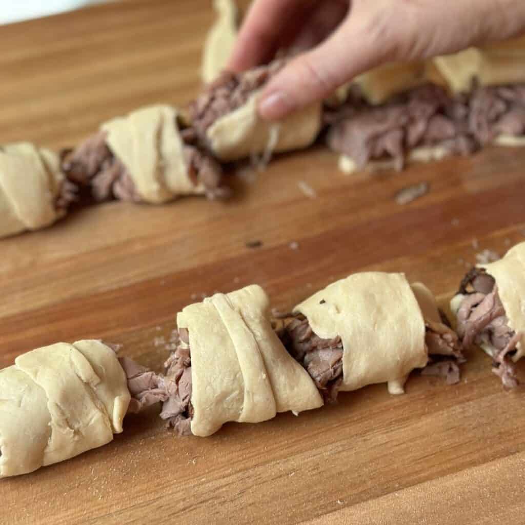 Rolling up steak and cheese bites with crescent roll dough.