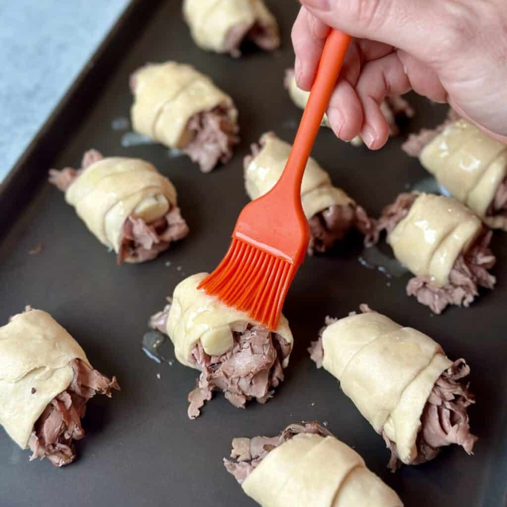 Brushing butter on crescent roll dough.