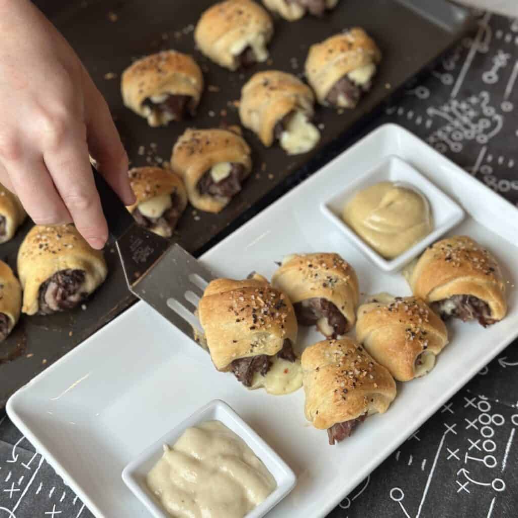 Placing steak and cheese bites on a plate.