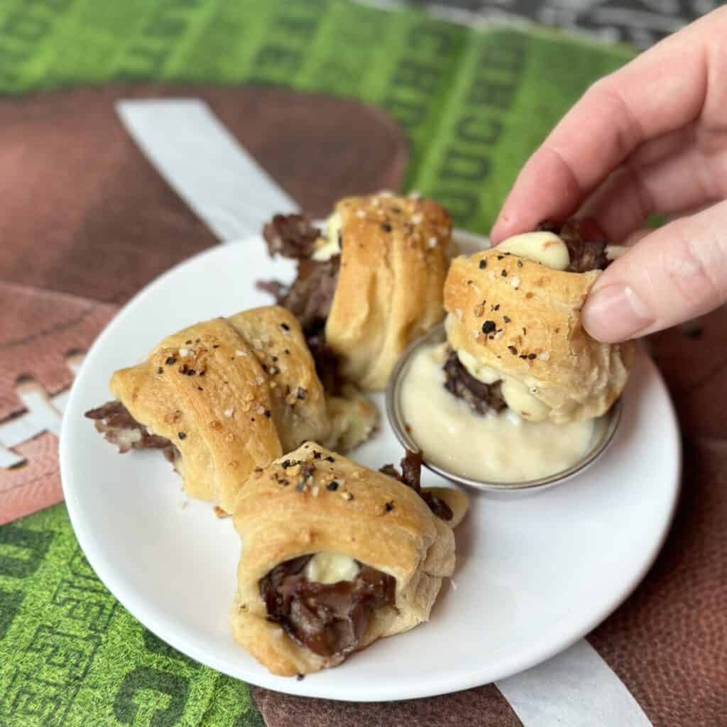 Dipping a steak and cheese crescent bite into horseradish sauce.