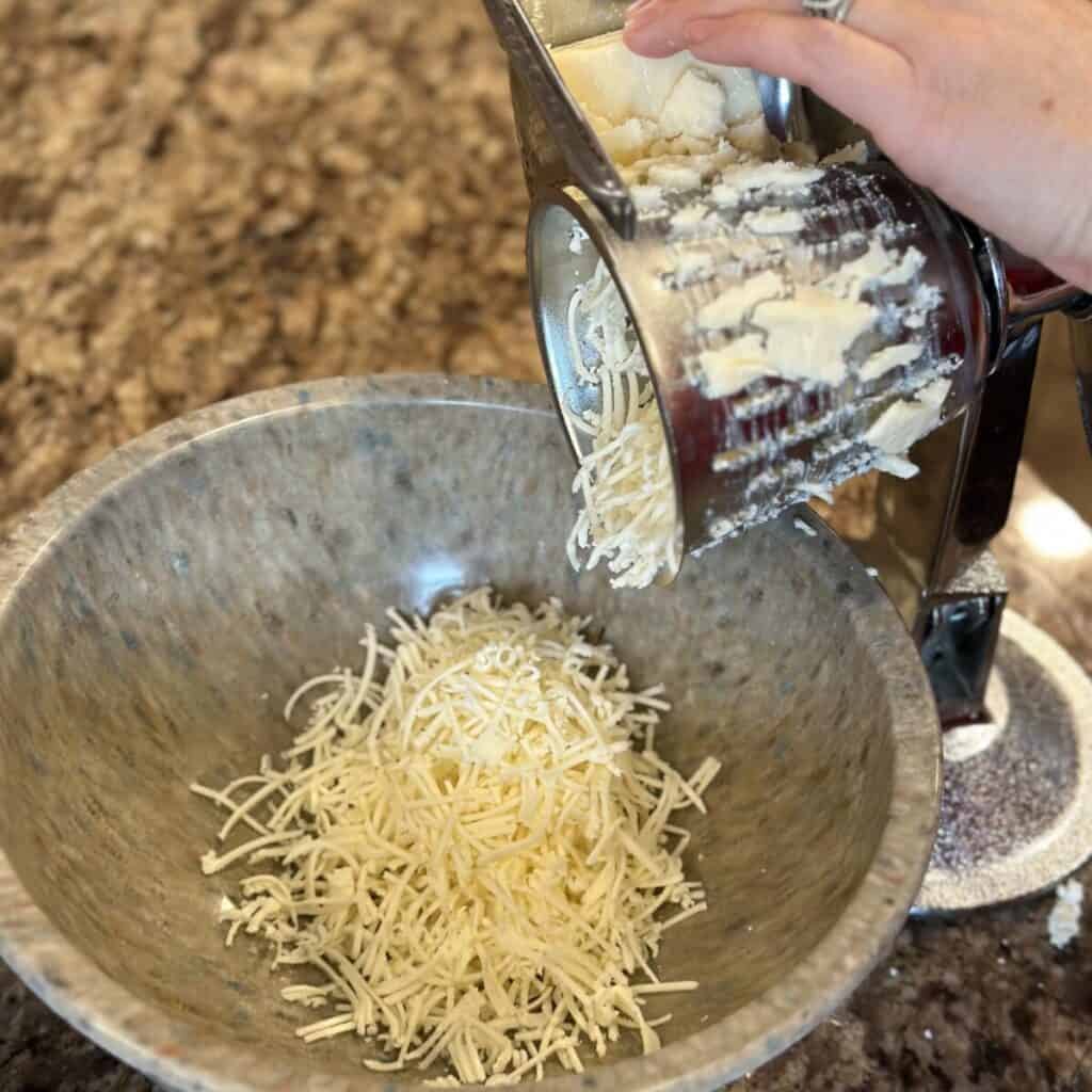 Grating cheddar cheese into a bowl.