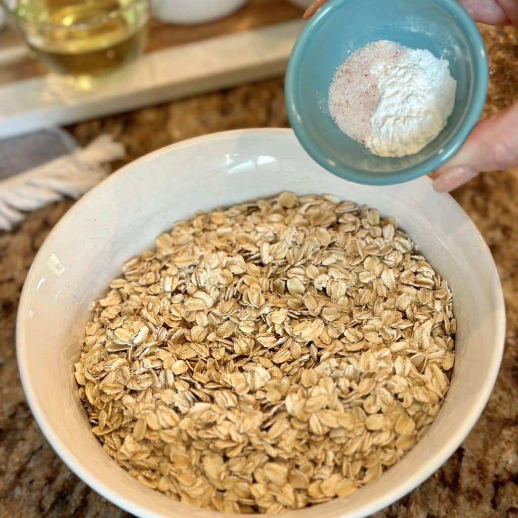 Adding baking and salt to oatmeal in a bowl.