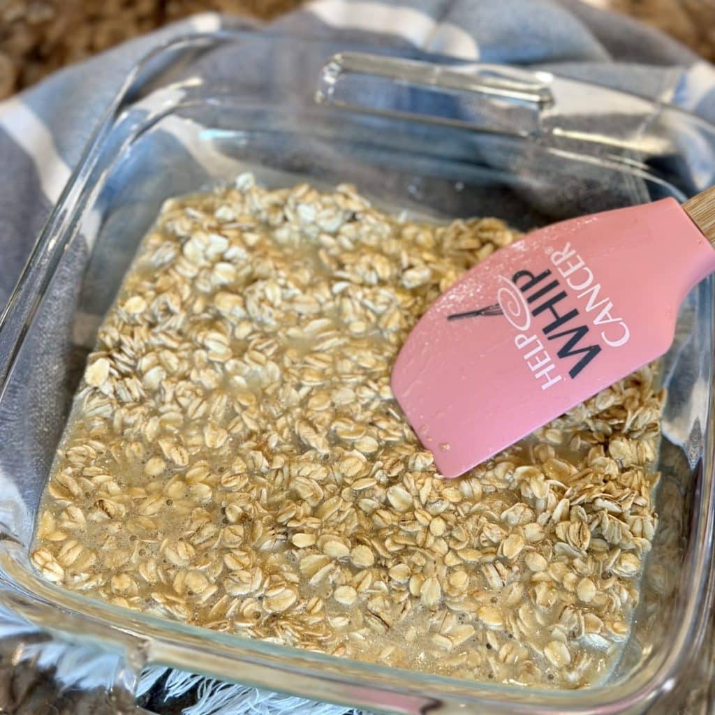 Spreading an oatmeal mixture in a baking dish.