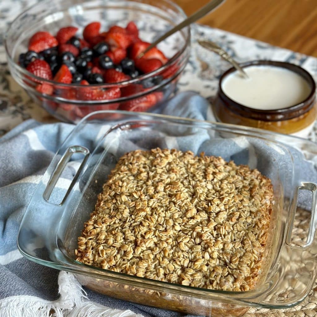 A dish of baked oatmeal with cream and berries.