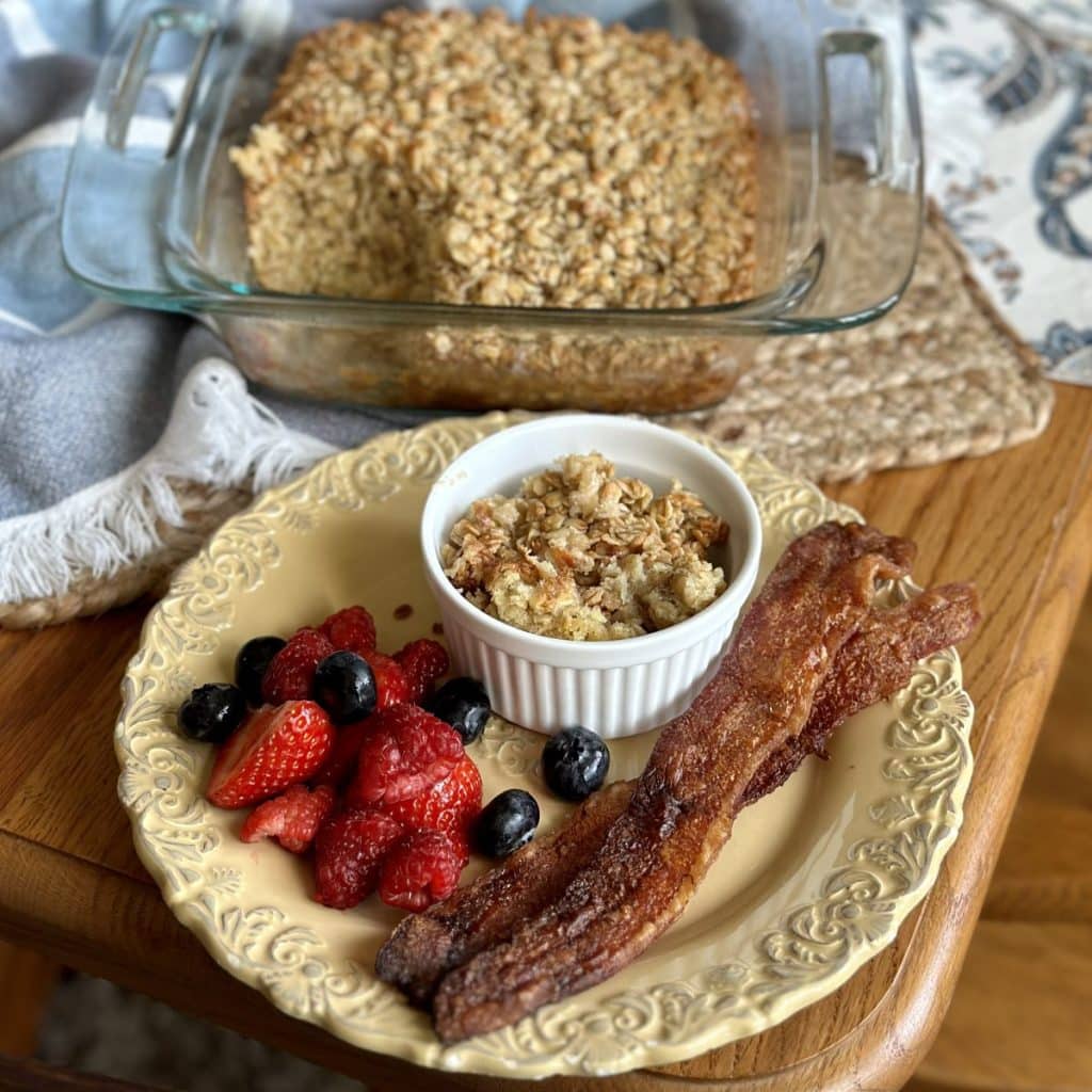 A plate with bacon, berries and bowl of oatmeal.
