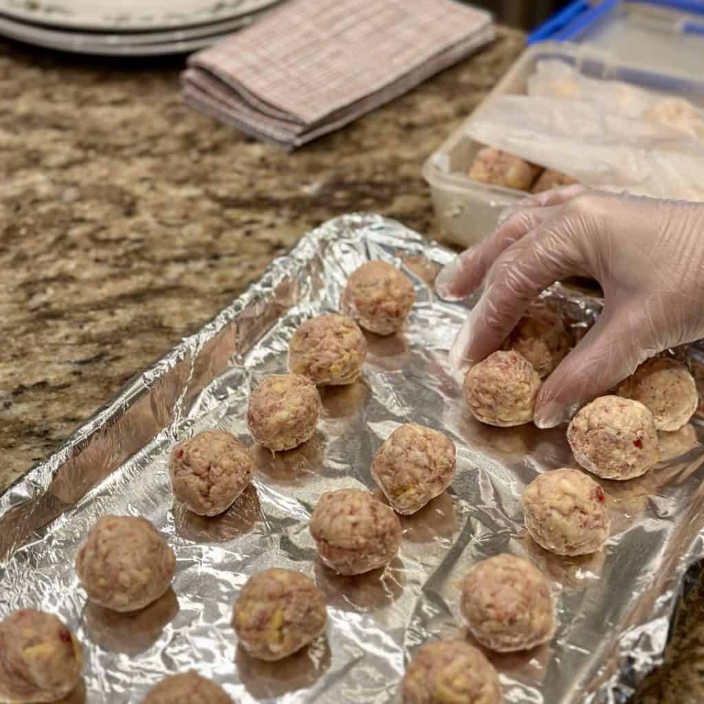 Placing sausage balls on a sheet pan.