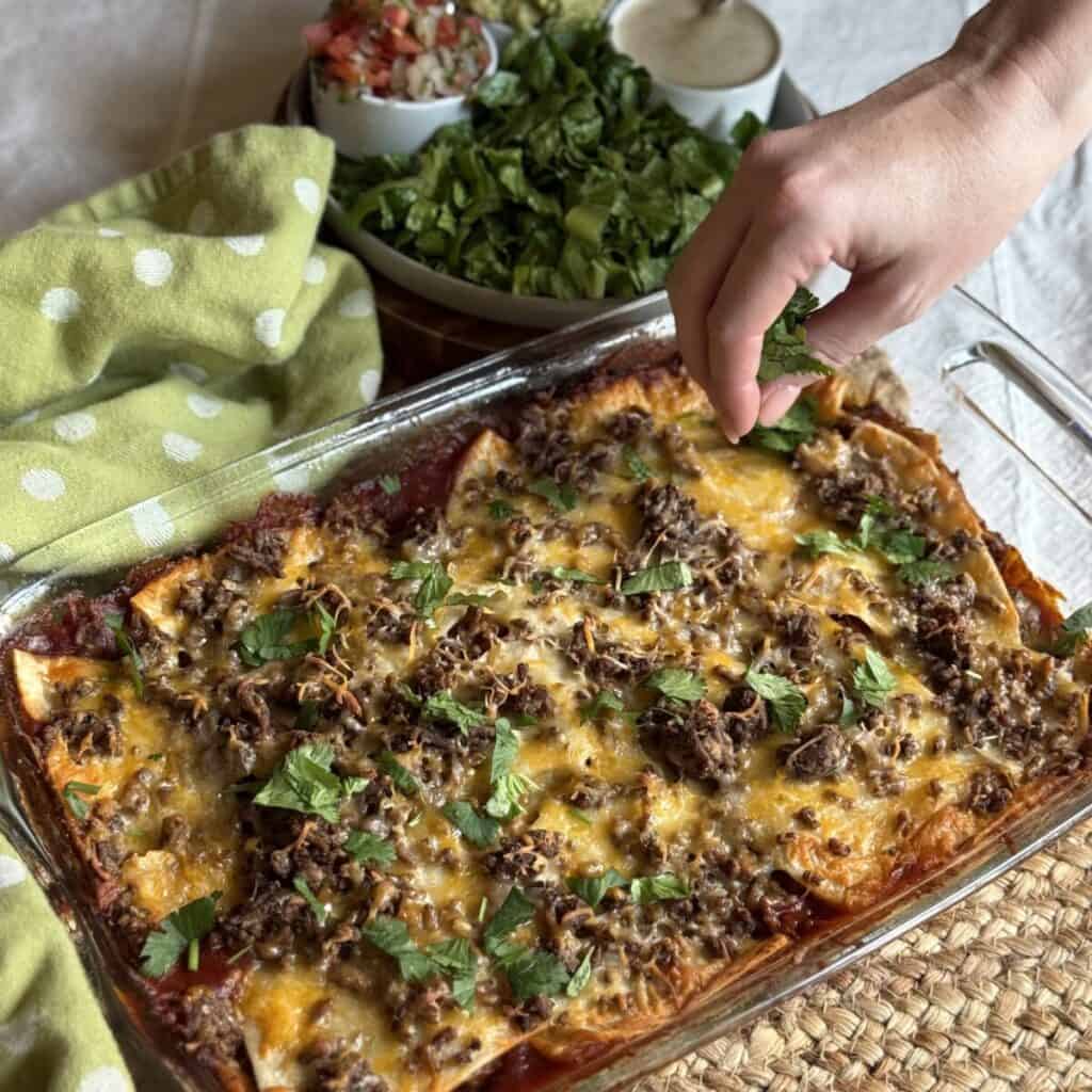 Sprinkling cilantro on taco lasagna.
