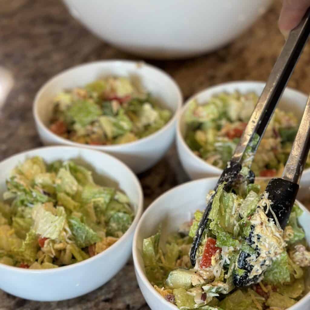 Adding salad to salad bowls.