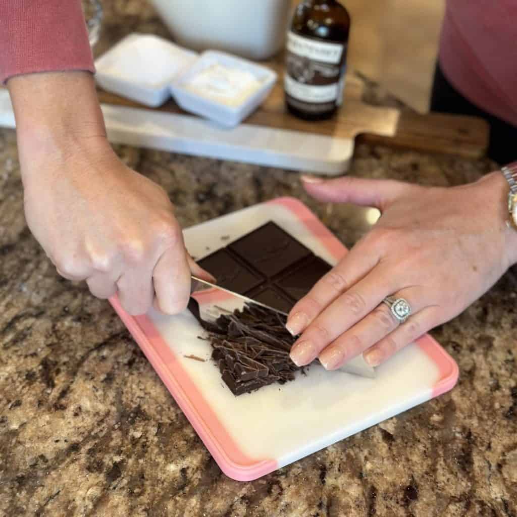 Chocolate being chopped on a cutting board.
