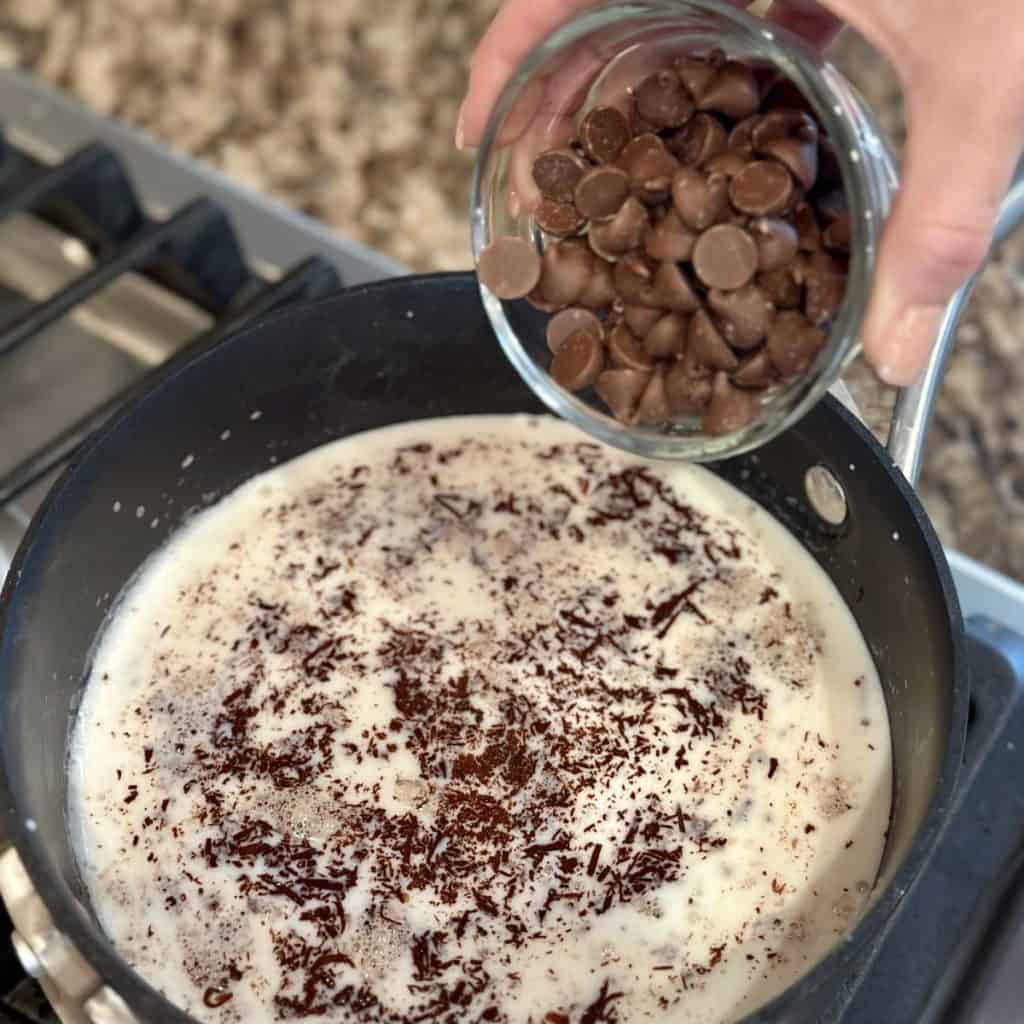 Adding chocolate to milk in a saucepan.