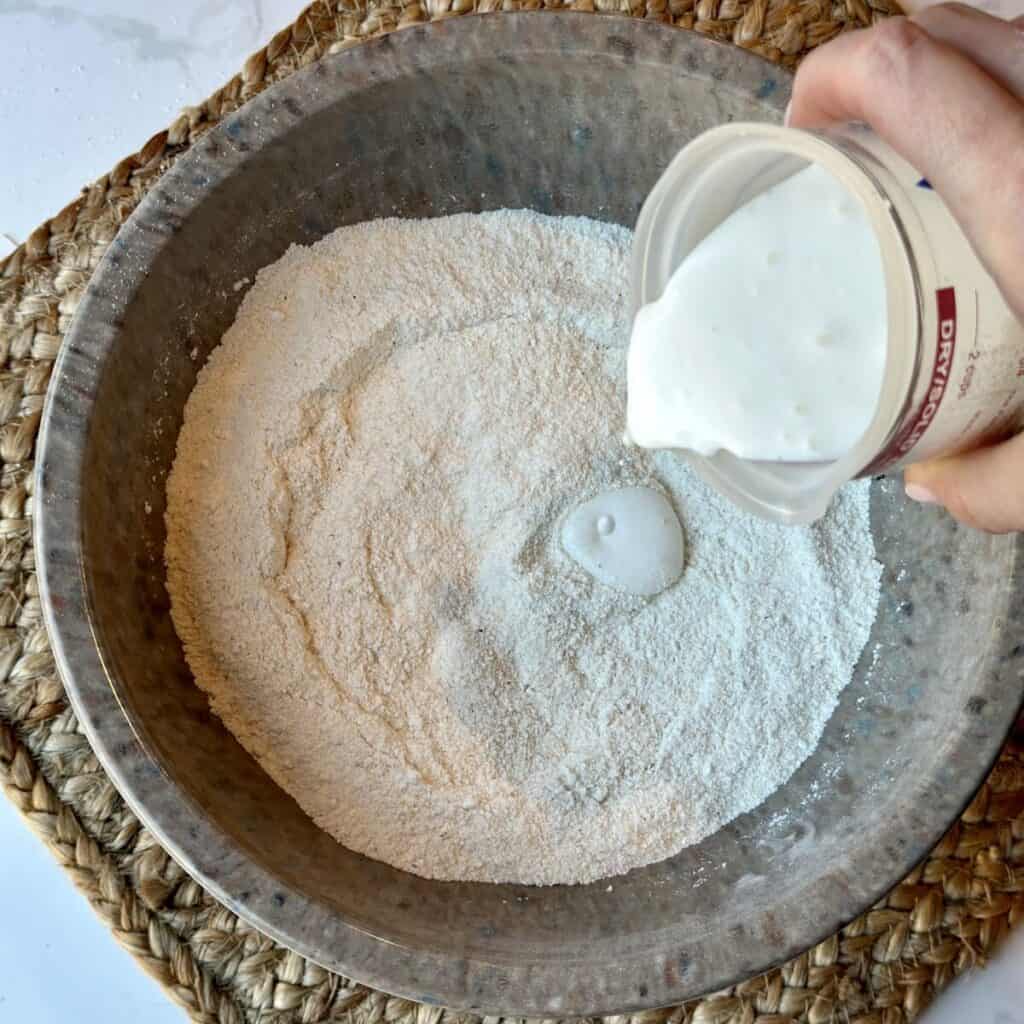 Adding buttermilk to flour in a bowl.