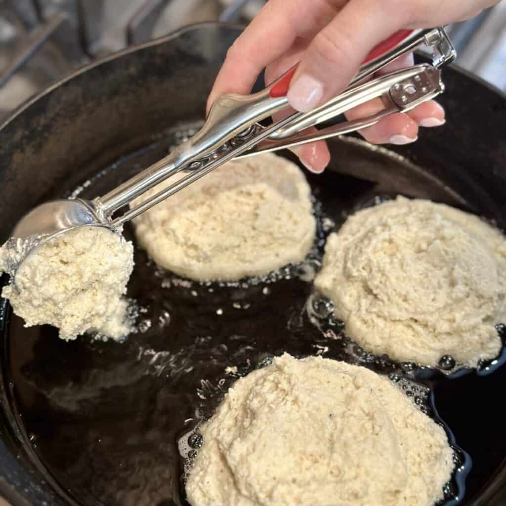 Adding hoecake batter in a cast iron skillet.