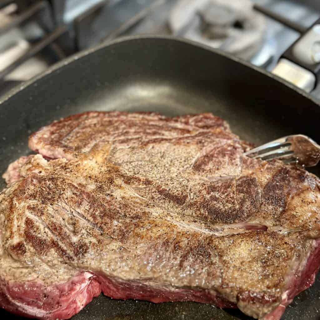 Searing a roast beef in a skillet.