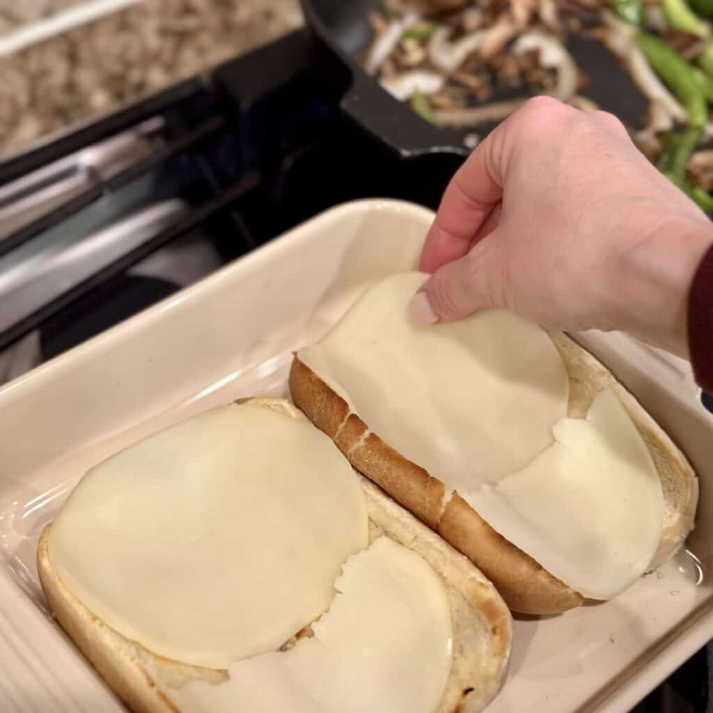 Laying cheese on hoagie buns.