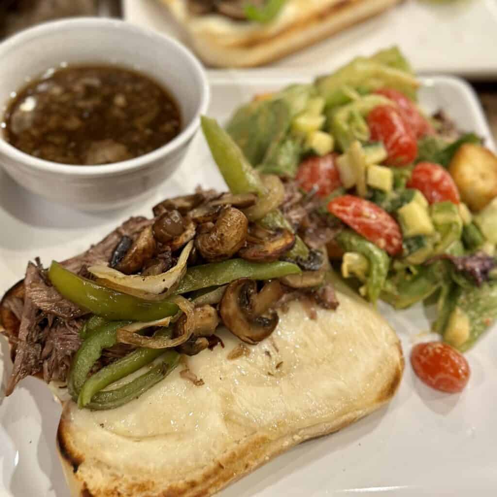 A French dip sandwich with a salad and au jus.