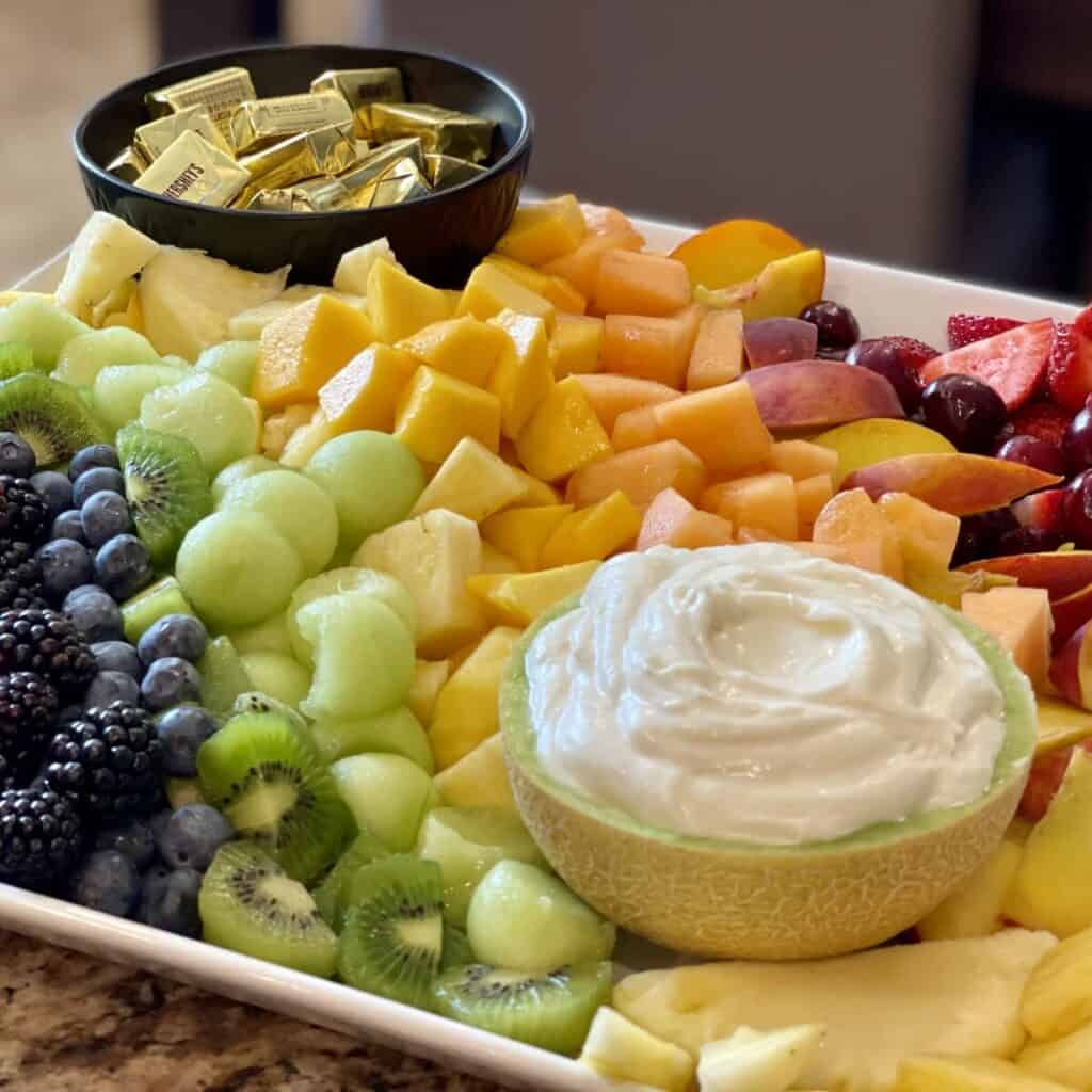 A tray of of fruit in the shape of a rainbow.