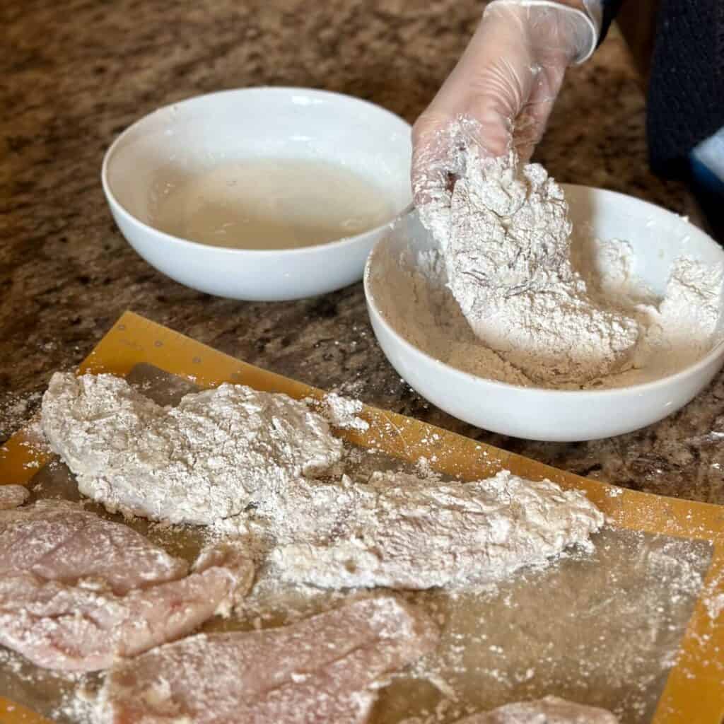 Dipping chicken in breading.