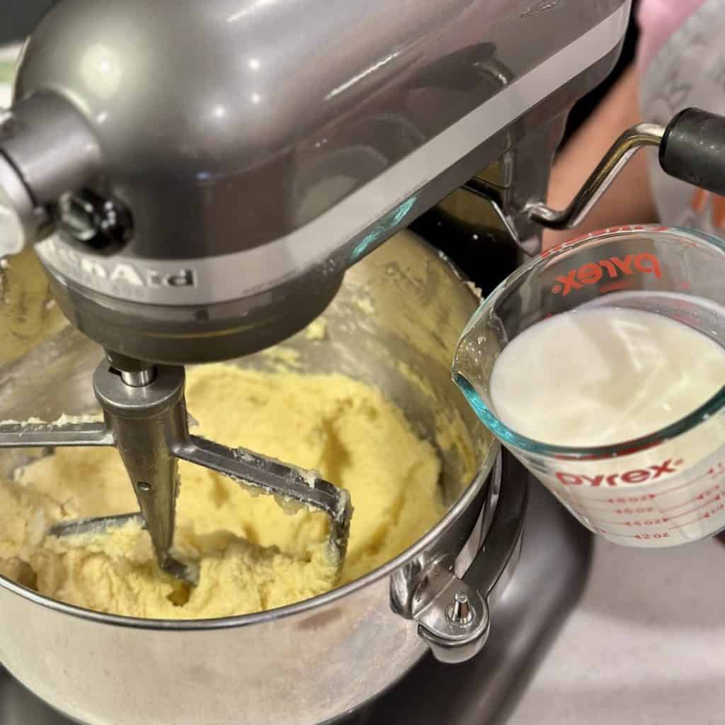 Adding milk to a mixer of cake batter.