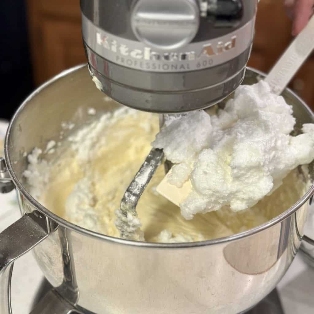 Adding whipped egg whites to cake batter in a mixer.