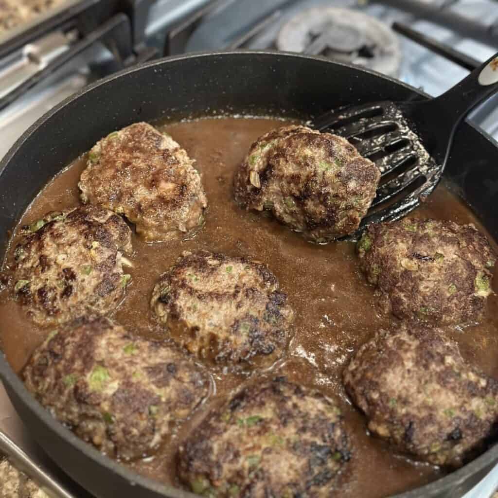 Flipping Salisbury steaks in gravy.