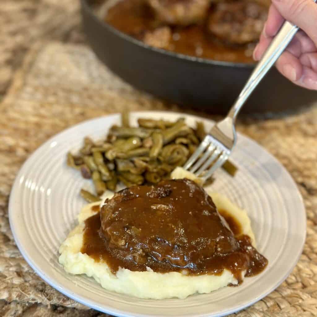 Getting a bite of Salisbury steak and gravy with potatoes.