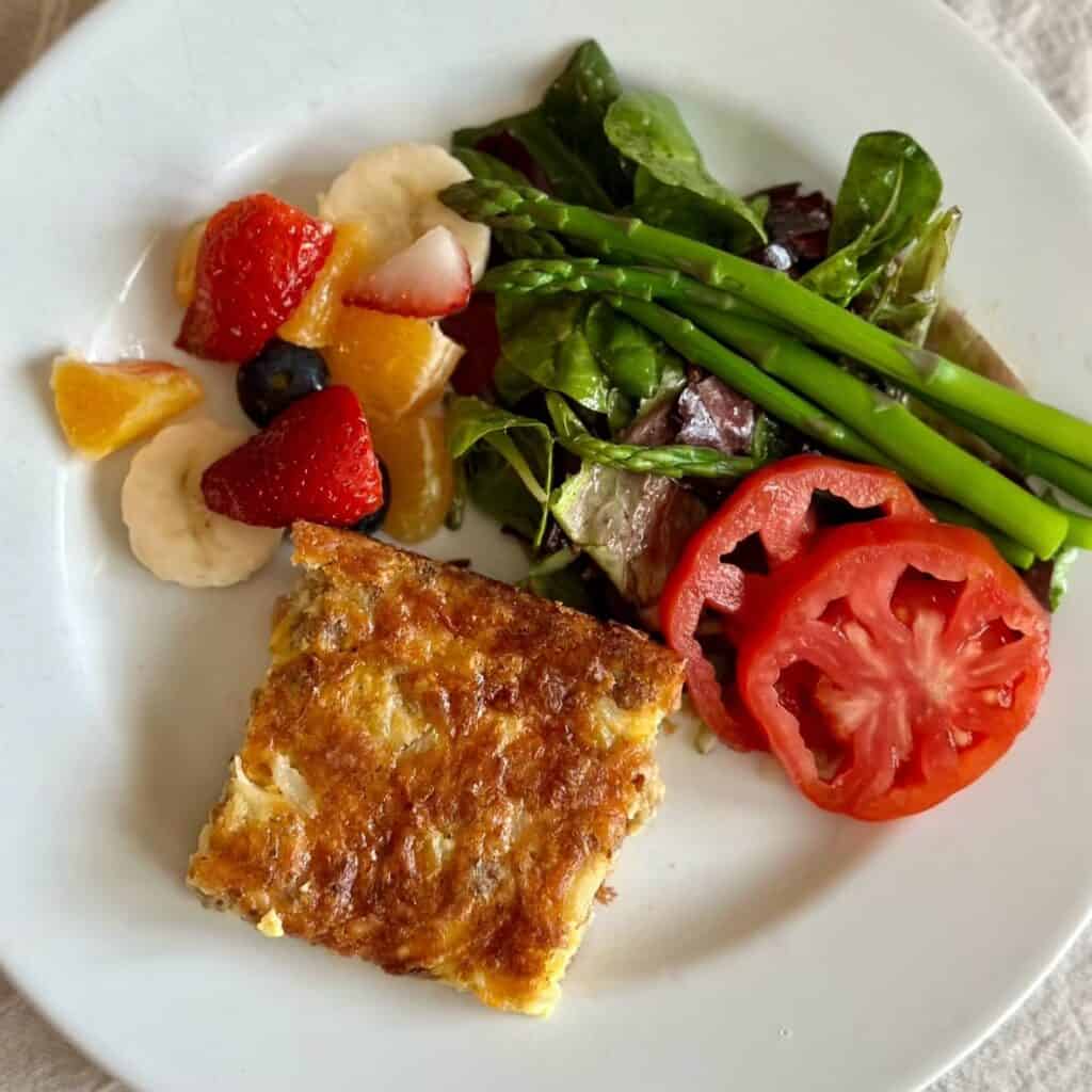 A serving of breakfast casserole with vegetables and fruit.