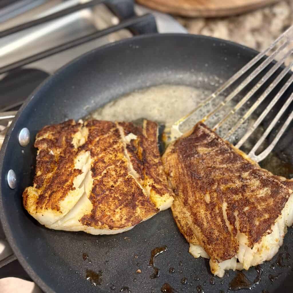 Flipping cod in a skillet.