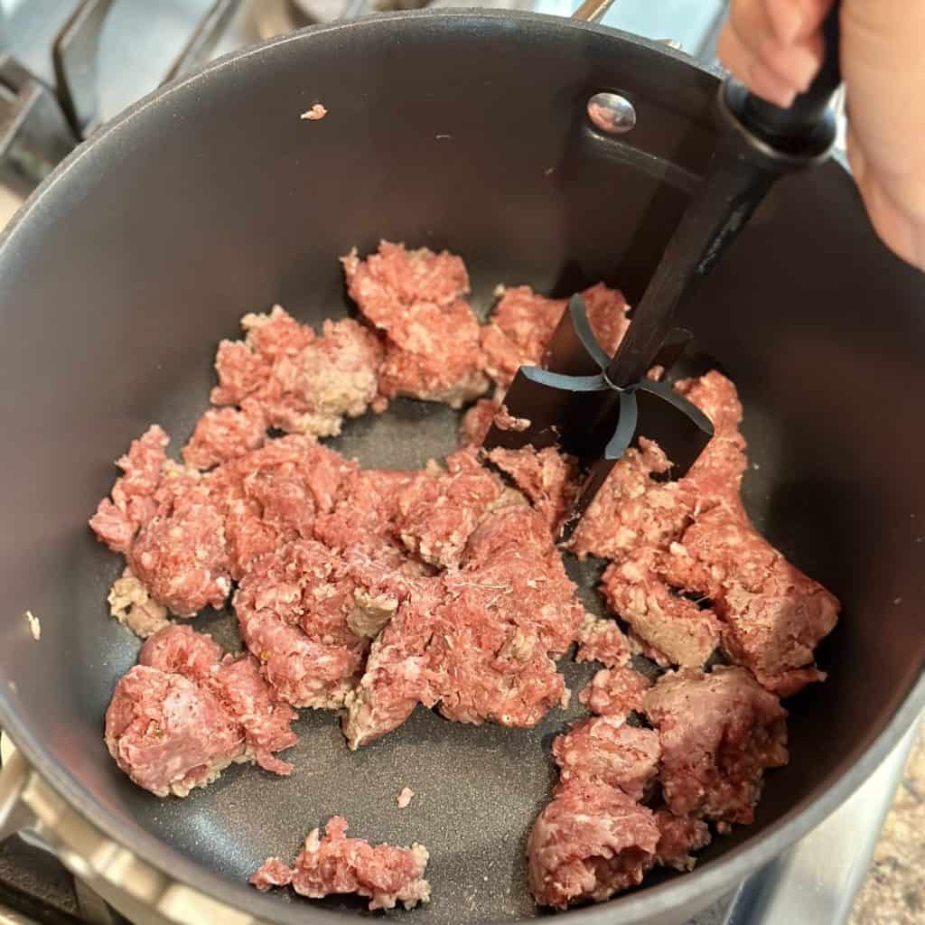 Crumbling sausage in a pan.