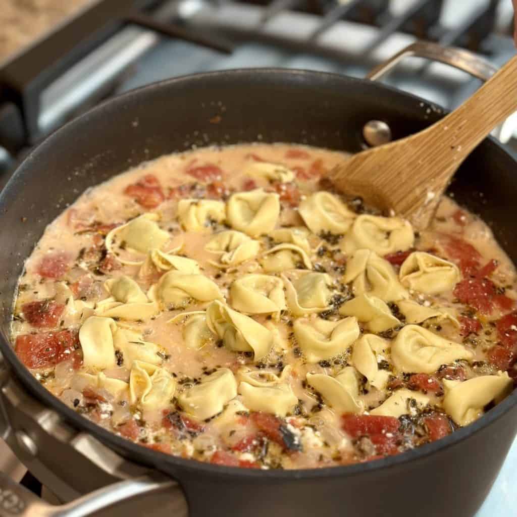 Adding tortellini to a pot of soup.