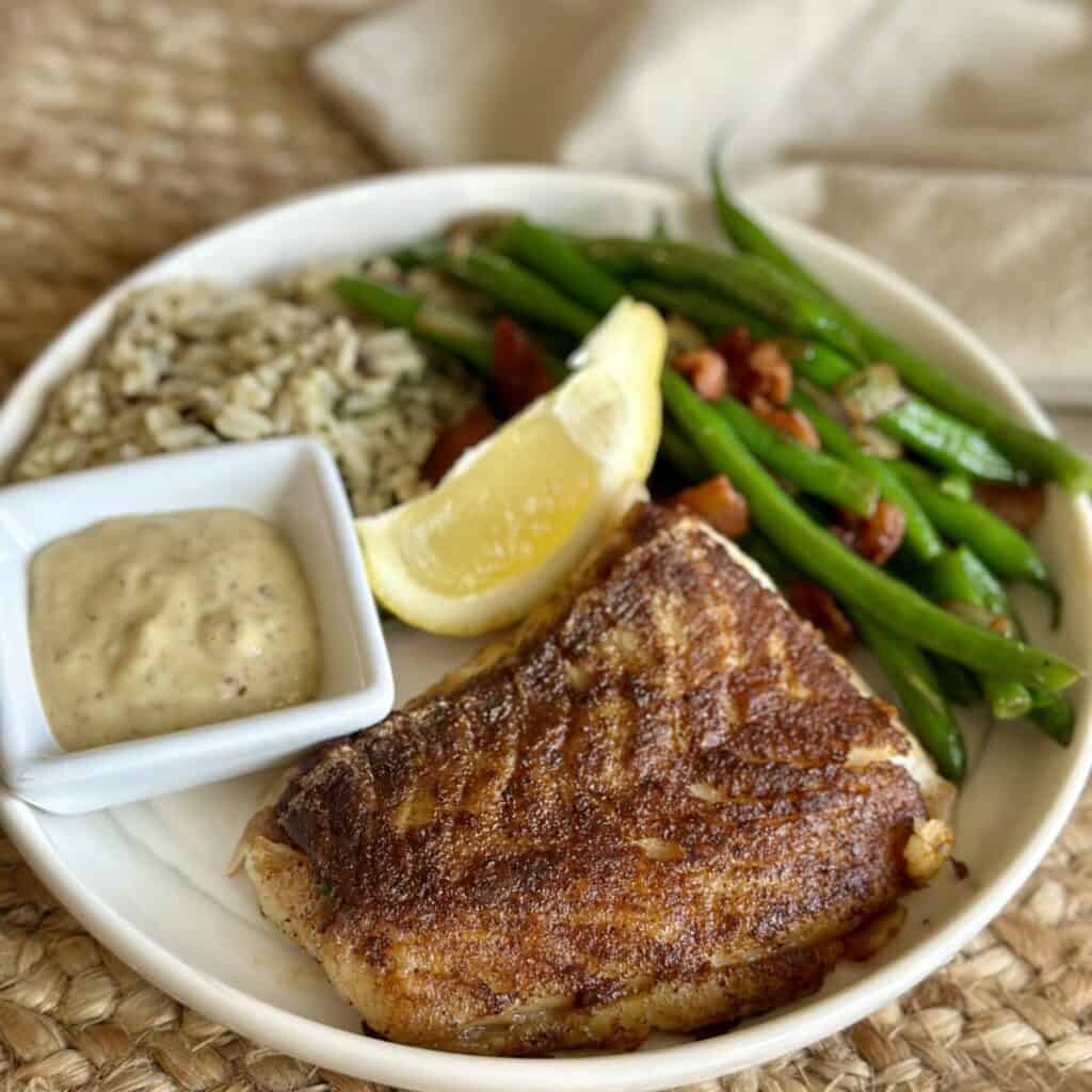 A dinner plate with fish, beans and rice.