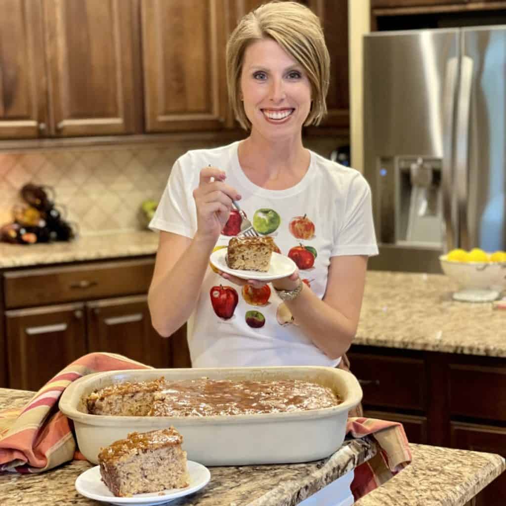 Laura holding a saucer with a slice of apple dapple cake on it.