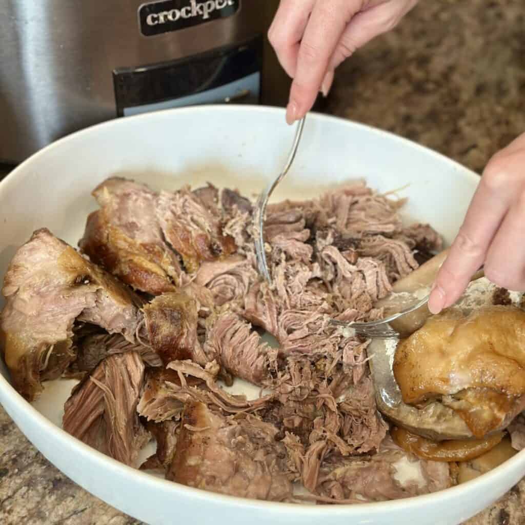 Shredding pork in a bowl.