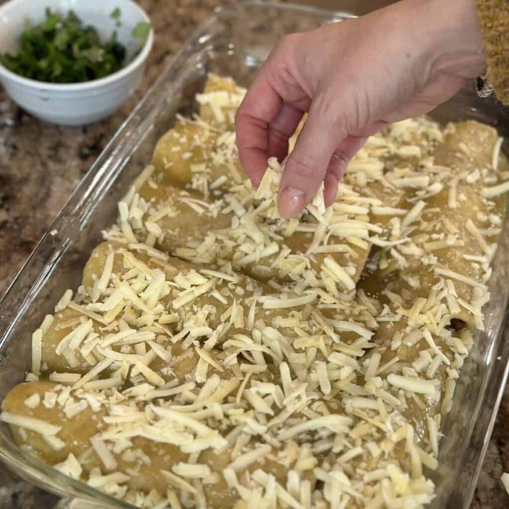 Sprinkling cheese on enchiladas.