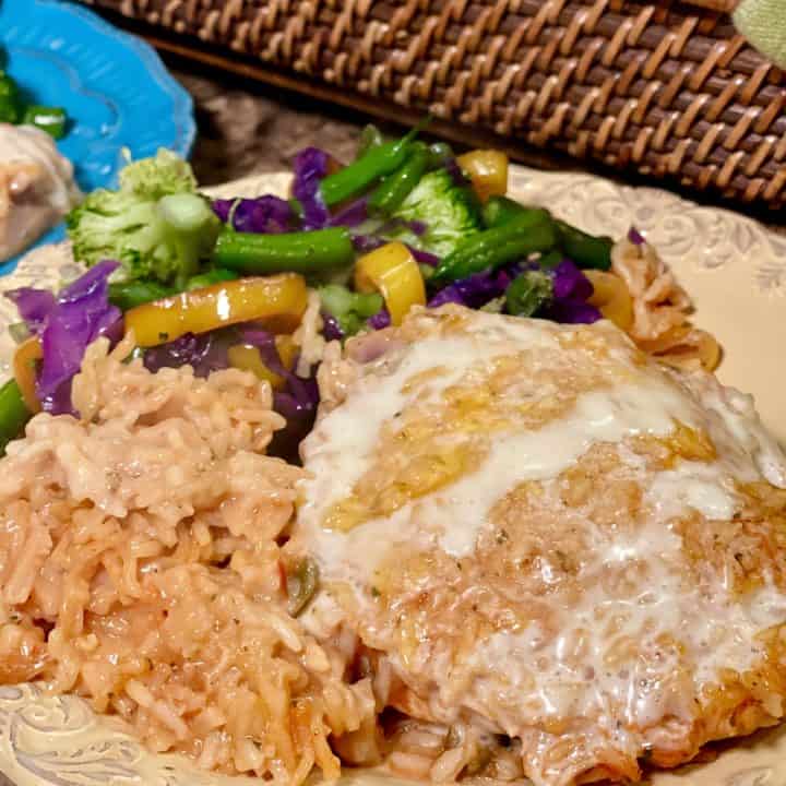 This is a picture of a plate of veggies, rice and chicken topped with queso.