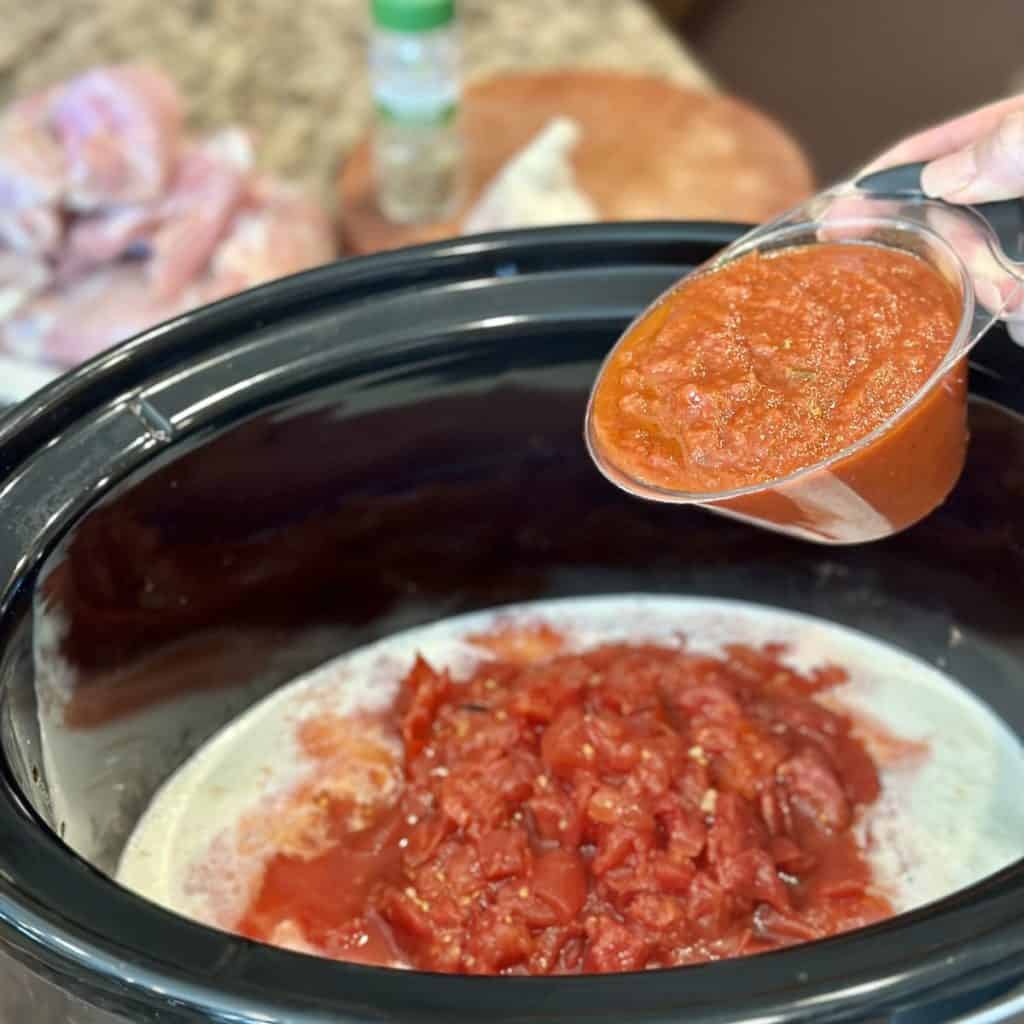 Adding marinara sauce to a crockpot.