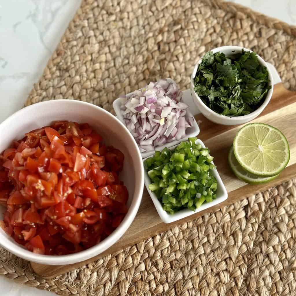 chopped ingredients for pico de gallo displayed on a cutting board