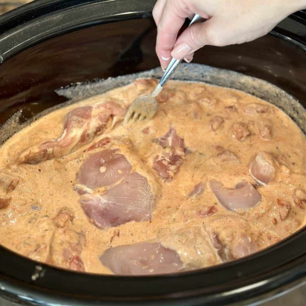 Adding chicken thighs to a crockpot.